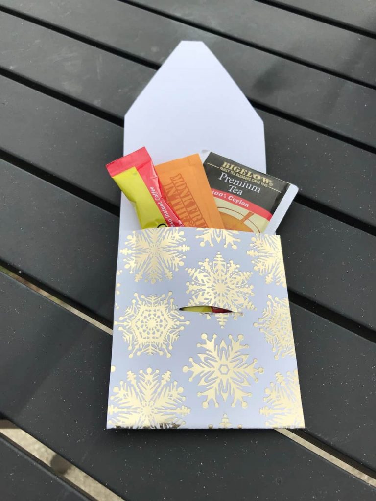 a snowflake gift envelope with some packets of coffee and tea in it on a brown table
