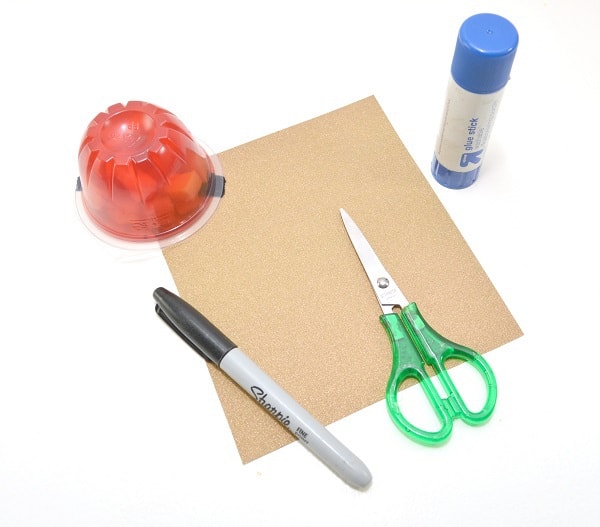 Jello snack cup, scissors, a black permanent marker,a glue stick, a small scrap of yellow or gold paper on a white background
