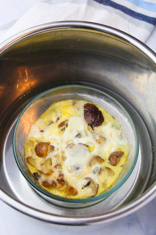 milk, eggs, shredded mozzarella, green peppers, mushrooms and potatoes in a glass bowl in an instant pot on a white cloth