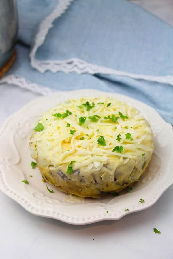 omelette casserole on a white plate on a white table next to a blue cloth