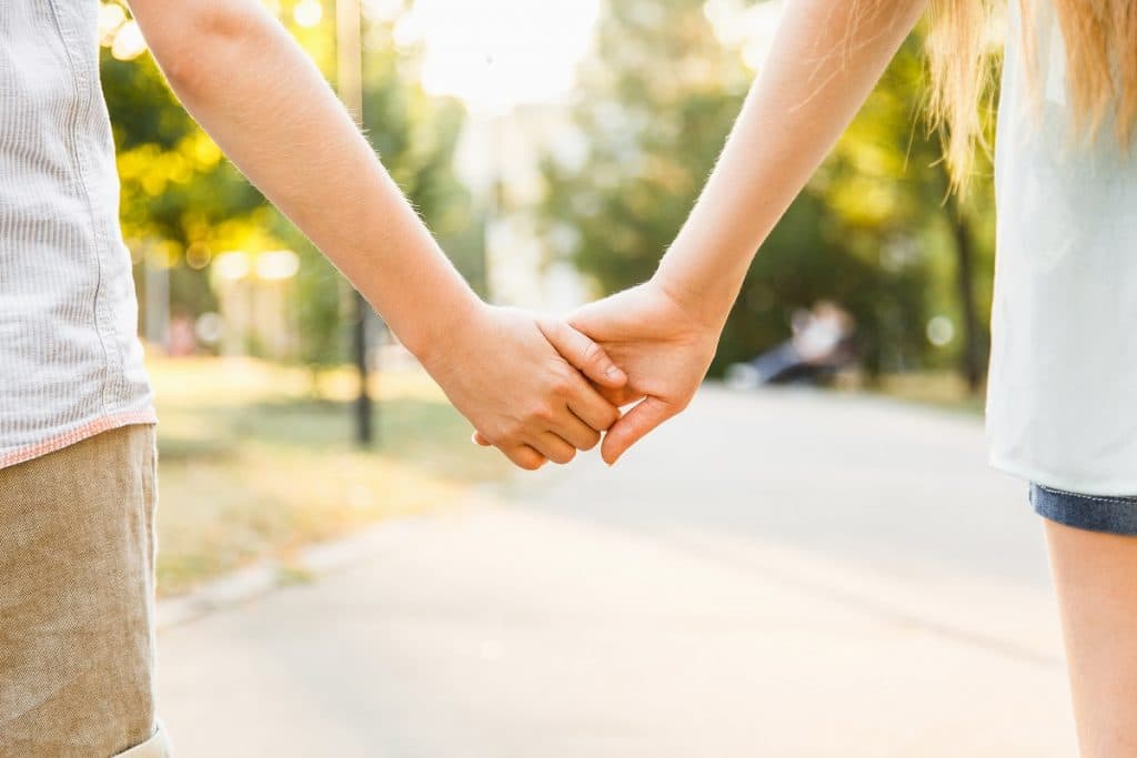boy and girl teen holding hands on a path outdoors