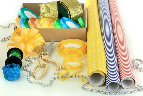 ribbon, beads, bows, scissors, wrapping paper on a white table