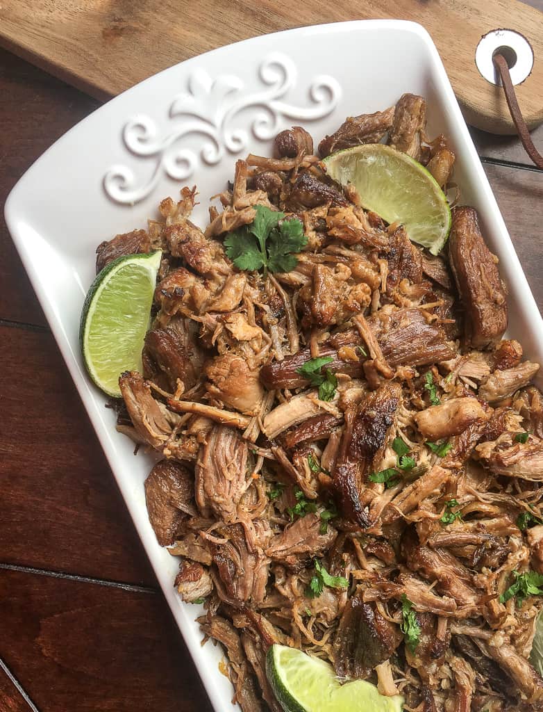 mexican pork recipe in a white dish on a brown wood table