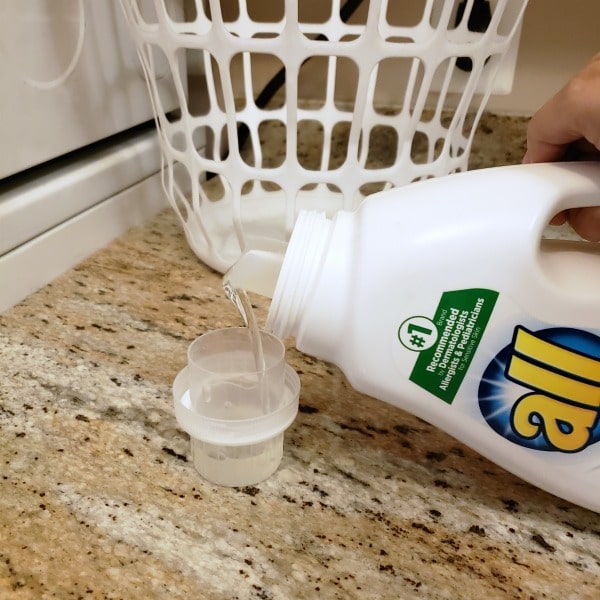 pouring all detergent into a plastic cap next to a white basket
