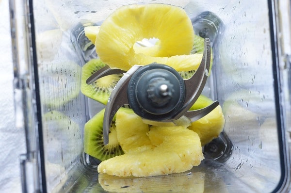 overhead view of sliced kiwi and pineapple in a blender
