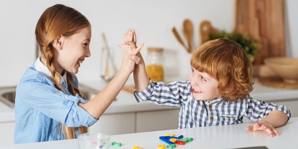 a boy and girl giving each other a high five in a kitchen