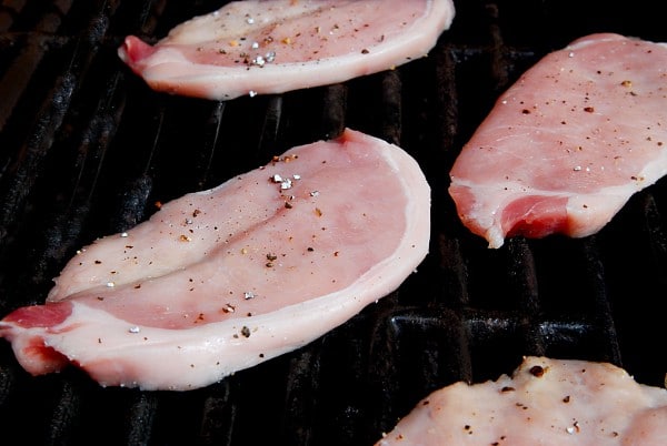 seasoned raw pork chops on a grilling rack