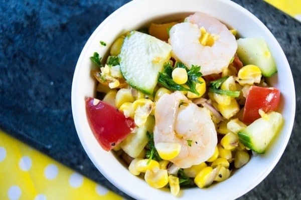 grilled corn salad with shrimp in a white bowl on a blue and yellow cloth