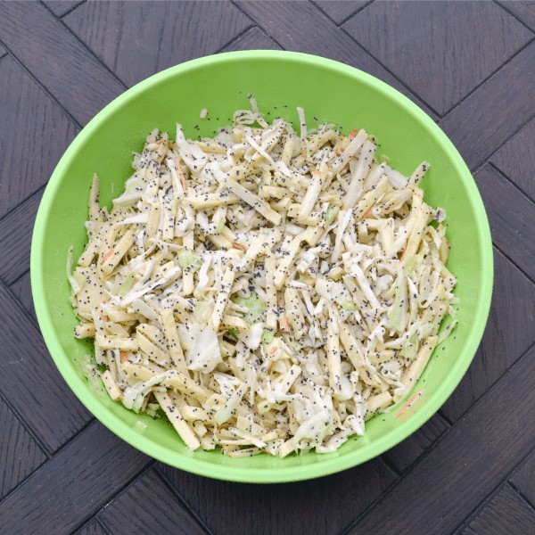 apple coleslaw in a green bowl on a wood background