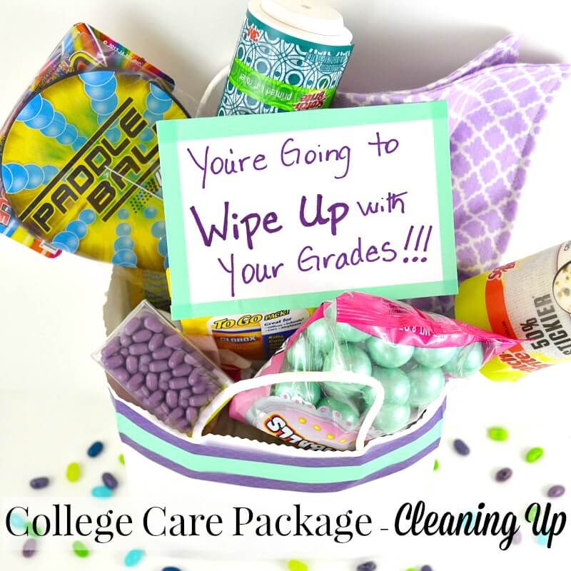 candy, tic tacs, paddle ball, paper towels, purple cloth in a paper bag on a white table with colored tic tacs on it with title text reading College Care Package Cleaning Up