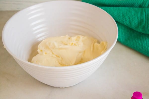 whipped heavy cream in a white bowl on a white table next to a green cloth