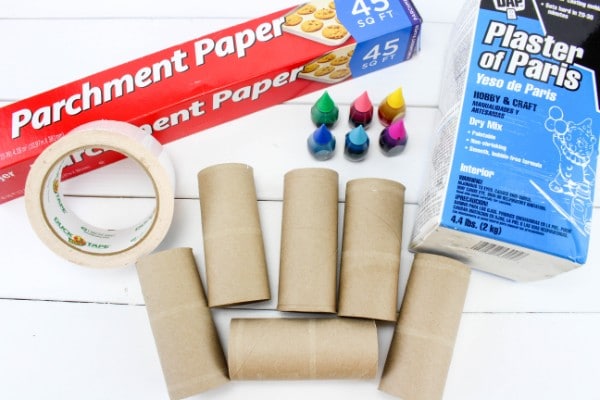 parchment paper, plaster of paris, food coloring, duct tape toilet paper rolls all on a white wood table