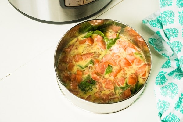 blt frittata in a round metal pan on a white wood table with an instant pot and green and white cloth in the background