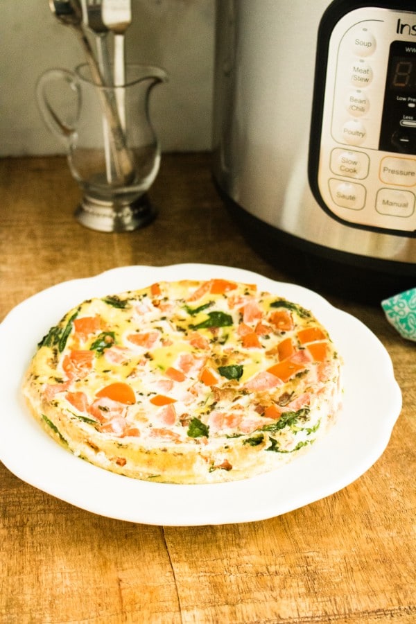 a blt frittata on a white plate on a wood table with an instant pot in the background