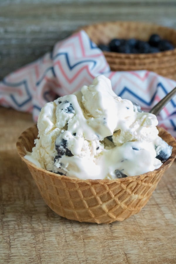 easy homemade lemon blueberry ice cream in a waffle bowl with blueberries in a waffle bowl in the background