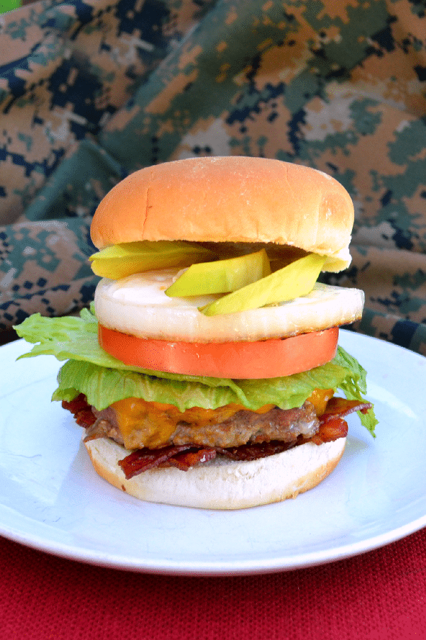 USO burger on a white plate on a brown table with camouflage clothing in the background