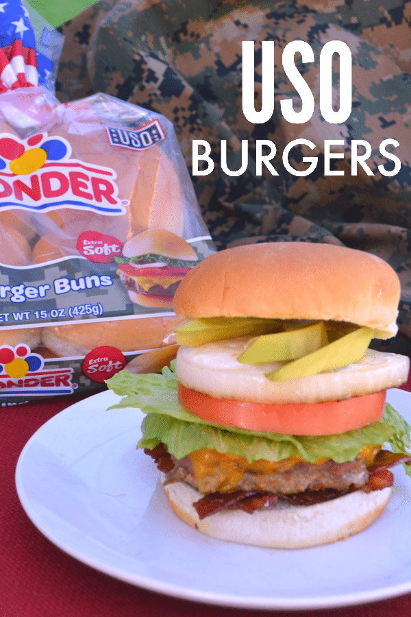 USO burger on a white plate on a brown table with a bag of wonder hamburger buns and camouflage clothing in the background with title text reading USO Burgers