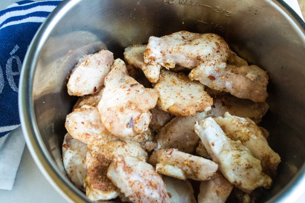 uncooked chicken wings sprinkled with Jamaican jerk seasoning in an instant pot