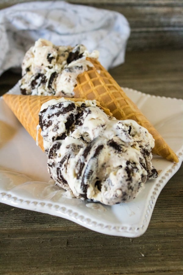 Two waffle cones filled with oreo ice cream on a square white plate