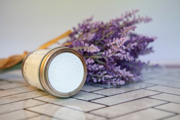 a mason jar of shoe powder next to a bunch of lavender on a tile floor