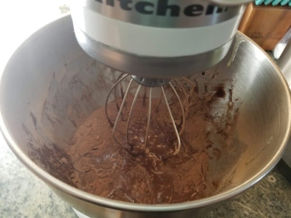 brownie batter being mixed in a mixing bowl with a kitchen aid mixer