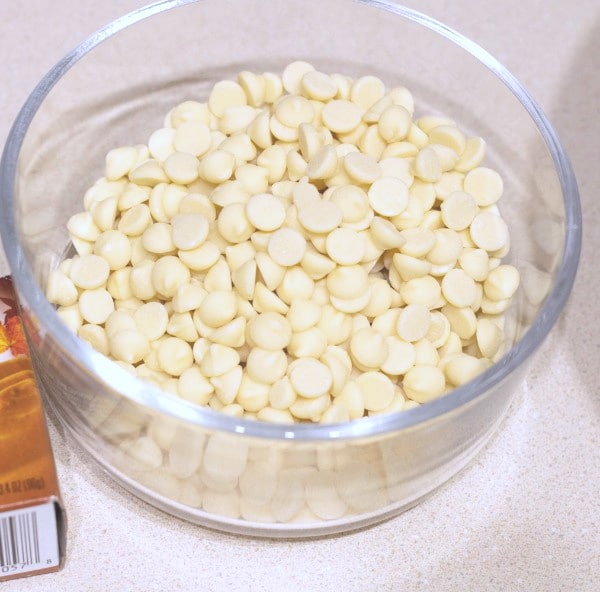 white chocolate chips in a glass bowl on a white counter