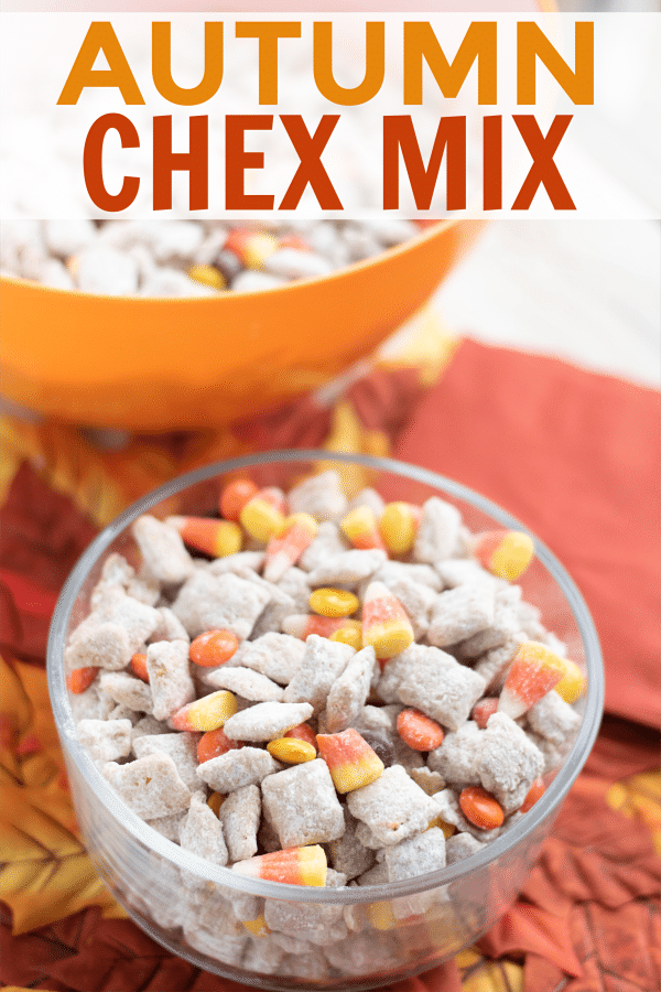 a glass bowl of chex mix with candy corn and m&Ms on fake leaves with an orange bowl of more chex mix and a napkin in the background with title text reading Autumn Chex Mix