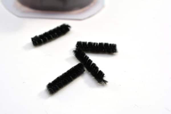 a black pipe cleaner cut into four pieces on a white table