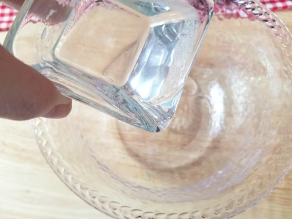 coconut oil being poured from one glass bowl to another on a table