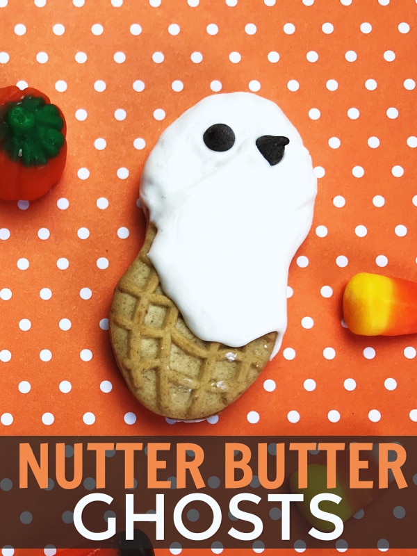 nutter butter decorated with white frosting and mini chocolate chips to look like a ghost on an orange and white polka dot background next to a candy pumpkin and candy corn with title text reading Nutter Butter Ghosts