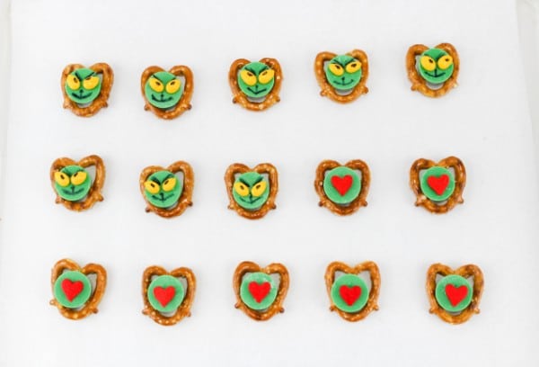 pretzels, green, red and yellow candy decorated to look like the grinch on a table