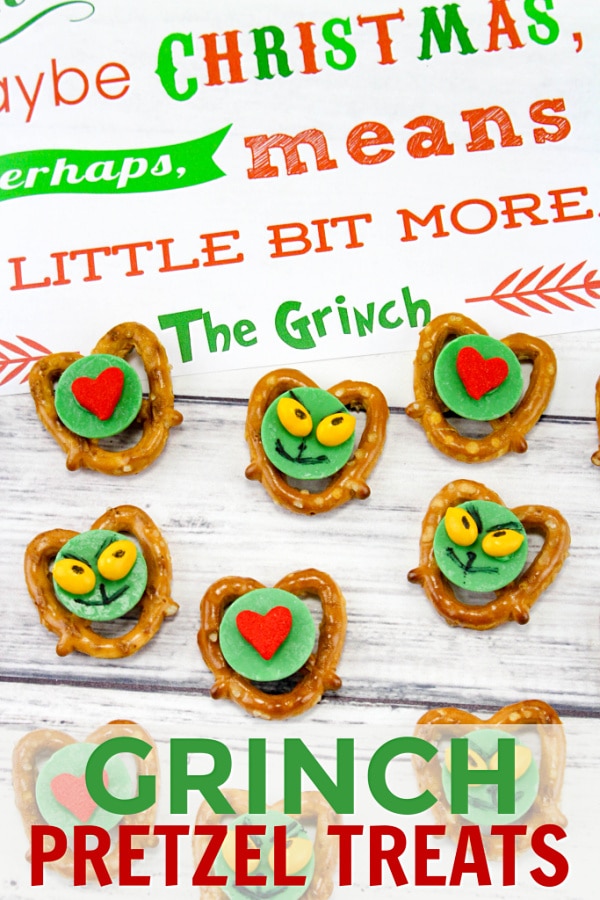 pretzels, green, red and yellow candy decorated to look like the grinch on a table with a phrase from the Grinch book written on a paper in the background with title text reading Grinch Pretzel Treats
