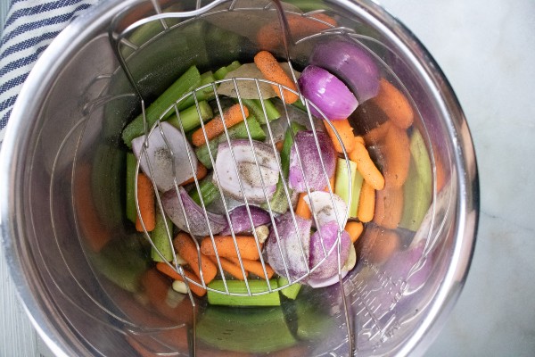 carrots, celery, onions and garlic in an instant pot with a metal trivet on top