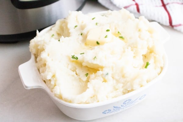 mashed potatoes in a casserole dish on a counter with an instant pot in the background