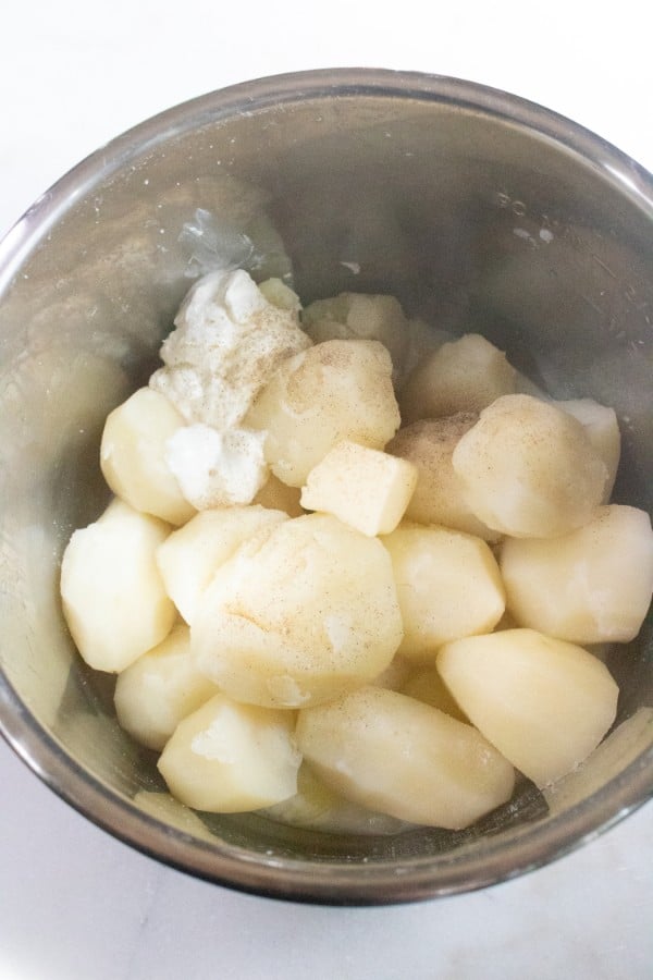 sour cream, milk, butter, and salt, pepper and garlic powder, and cooked potatoes in an instant pot on a white counter