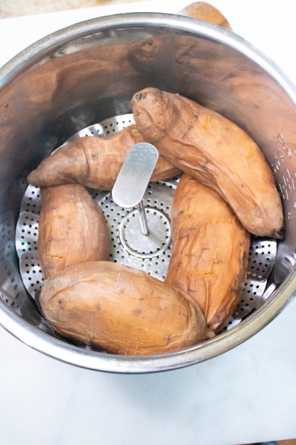 sweet potatoes on a steamer basket in an instant pot on a white counter