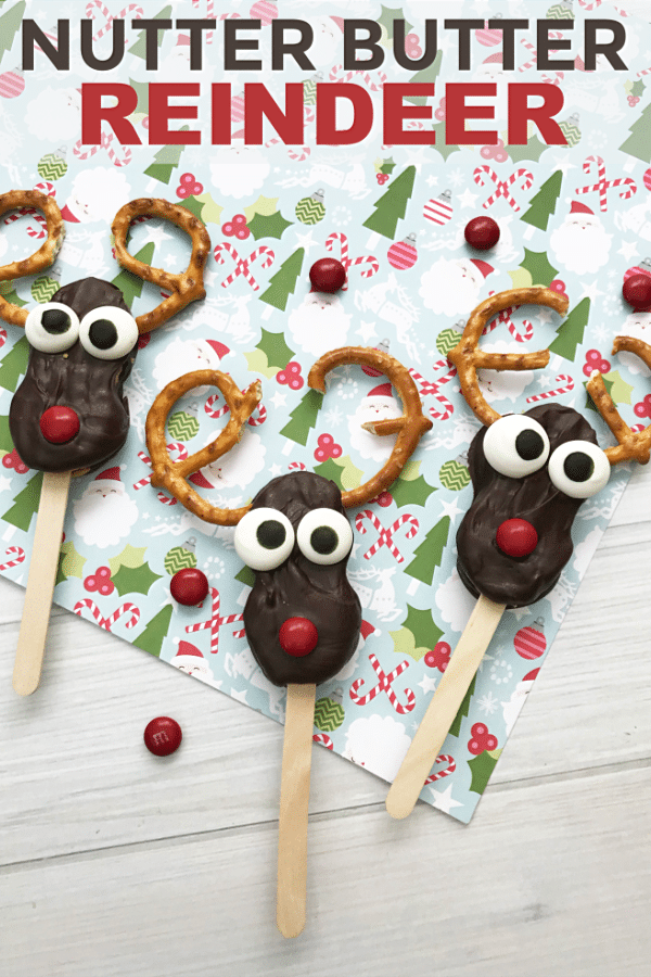 nutter butter cookies covered in chocolate with candy eyes, a red M&M nose, pretzel antlers on a popsicle stick on a Christmas paper background with title text reading Nutter Butter Reindeer