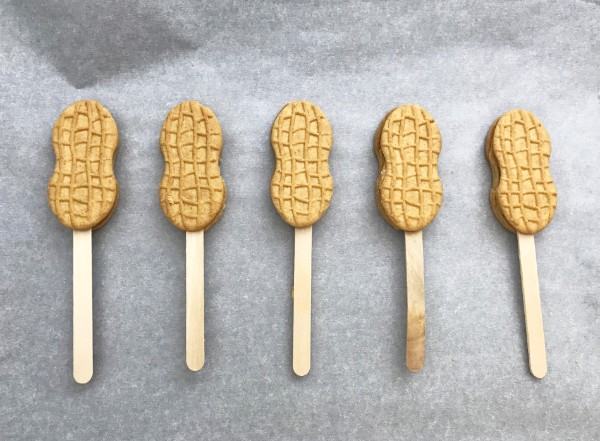 nutter butter cookies with a popsicle stick in the middle of them on a gray background