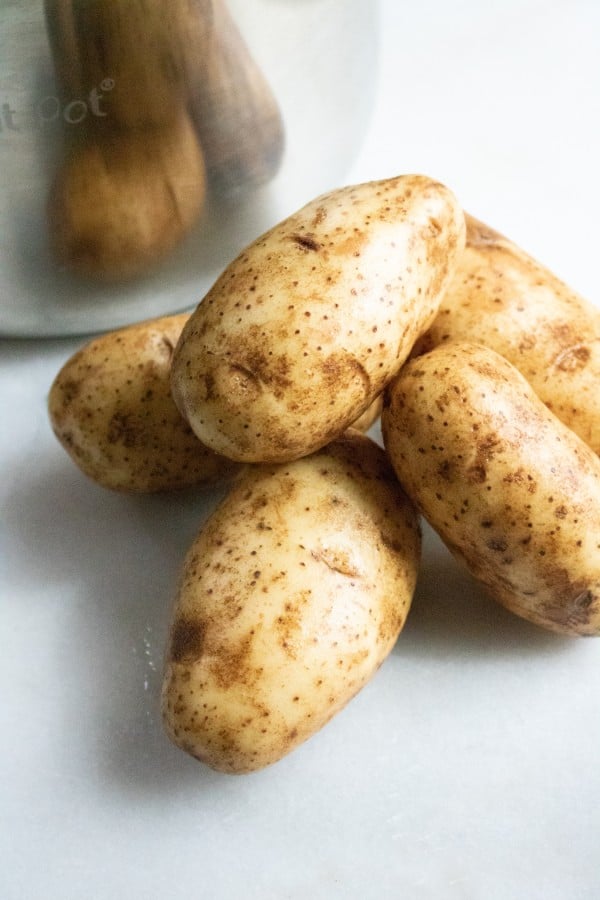 five potatoes on a white counter next to an instant pot