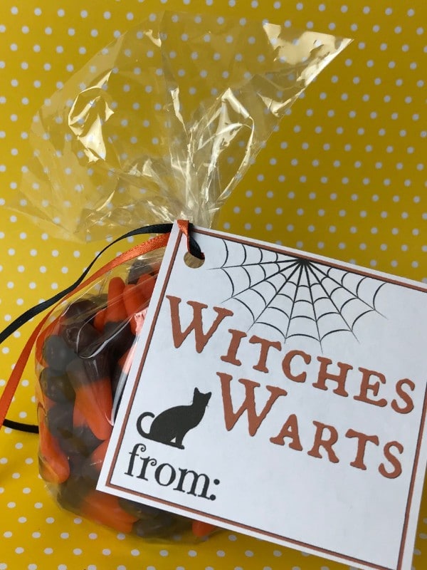 candy corn in a plastic bag with a label on it with text reading Witches Warts on a yellow and white polka dot background