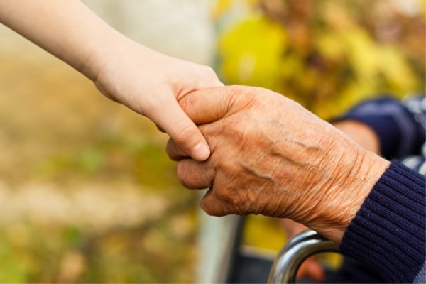 a younger person holding the hand of an older person