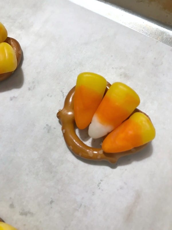 pretzels topped with three candy corn on a metal tray