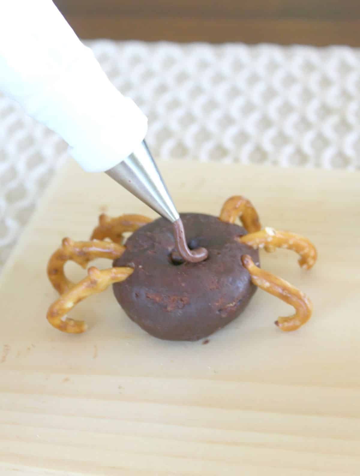 A person is putting chocolate on a mini donut.