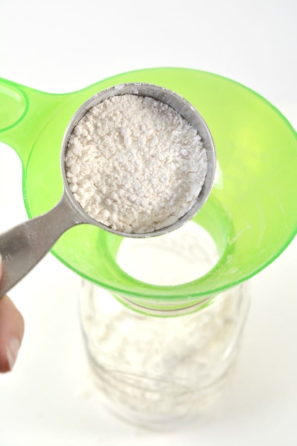 flour being poured into a glass jar through a funnel