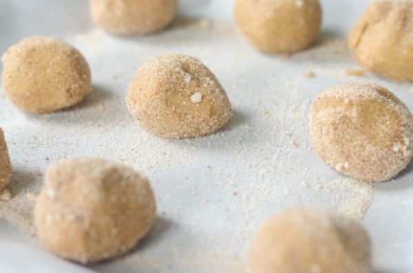 eggnog snickerdoodle dough in balls coated with sugar on parchment paper