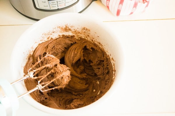 chocolate, cream cheese and sugar mixed together in a mixing bowl with beaters in it