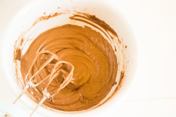 chocolate cheesecake batter in a mixing bowl with beaters above it
