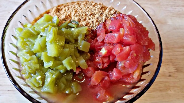 a glass bowl of taco seasoning, salsa, tomatoes, and green chilies