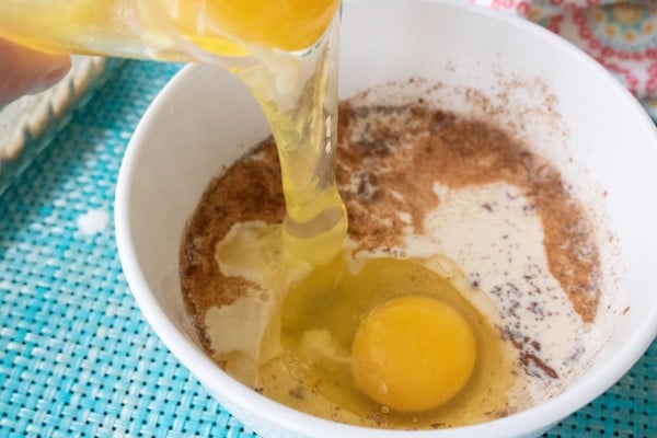 eggs being poured into a bowl of brown sugar, cinnamon and milk
