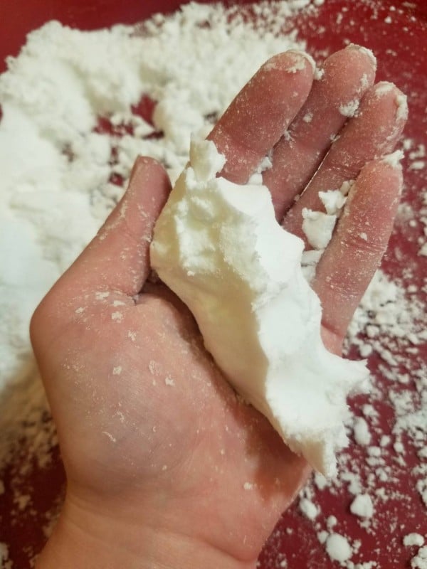 a hand holding fake snow with more fake snow underneath